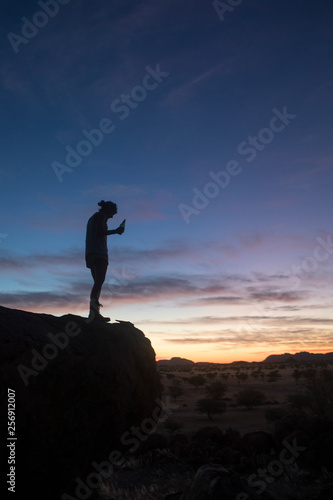 A tourist enjoying the sunset while camping in Namibia.