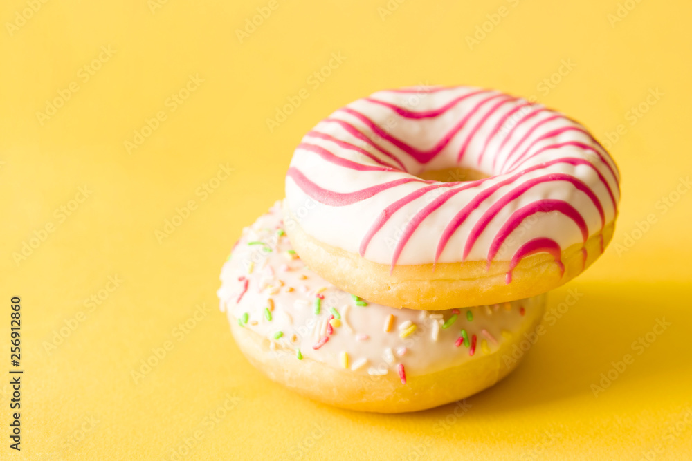 Two colorful donuts on yellow background, closeup Two colorful donuts on yellow background, closeup