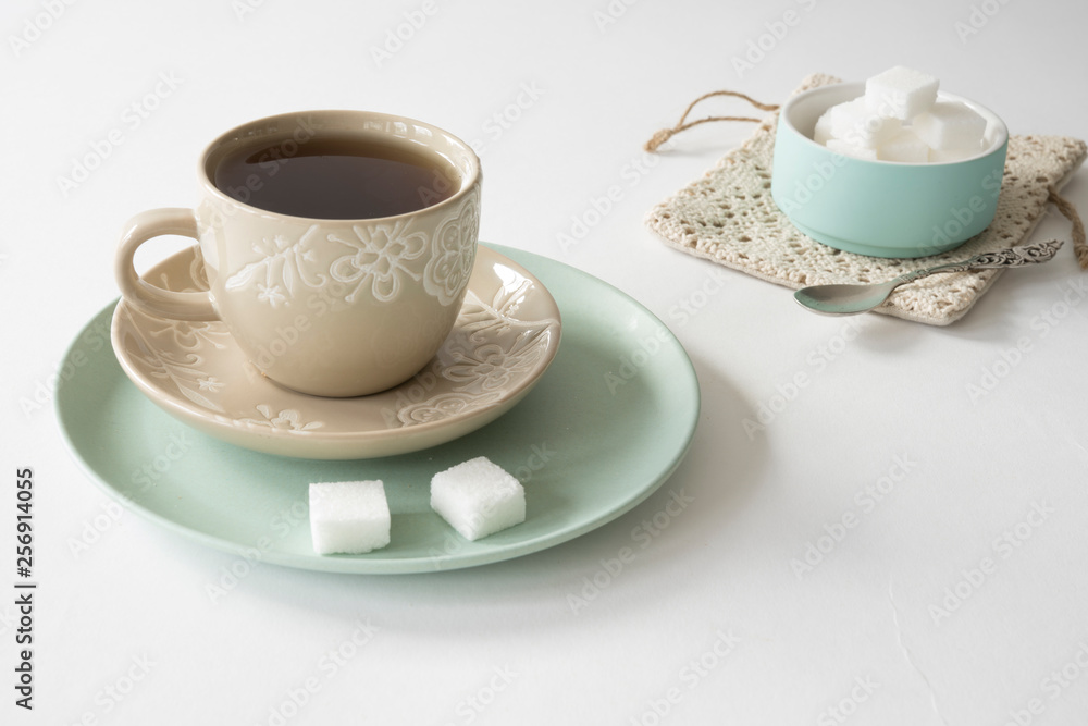 romantic breakfast scene with cup and saucer, tea, mint green bowl with sugar cubes romantic breakfast scene with cup and saucer, tea, mint green bowl with sugar cubes