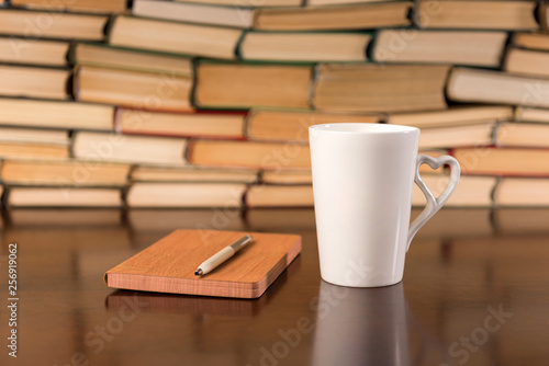 Old books on wooden table with tea and open notebook