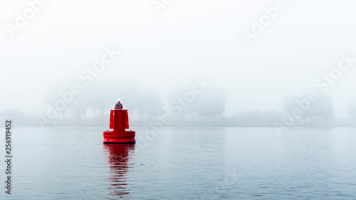Red buoy in a river in the mist photo