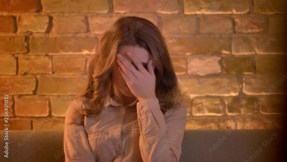Portrait of attentive young teenage girl watching TV and covering her eyes by hand in fear sitting in the living room. Portrait of attentive young teenage girl watching TV and covering her eyes by hand in fear sitting in the living room.