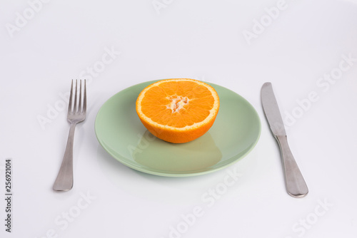half an orange on a plate isolated on white background