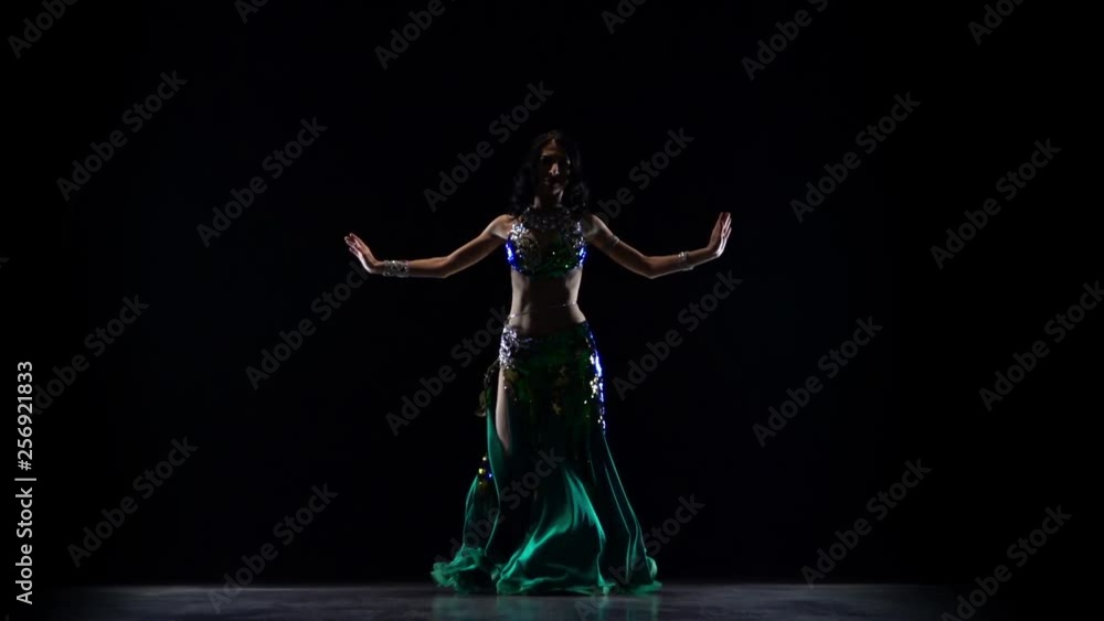 Female belly dancer who is starting shaking her hips. Black background. Slow motion Female belly dancer who is starting shaking her hips. Black background. Slow motion