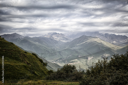 Mountain green valley with a deep gorge, high mountains and hills covered with grass, rocky gorge with a mountain river at the bottom. Landscapes of Georgia, Georgian military road.