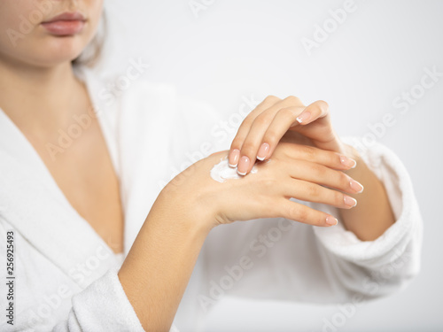 Woman applies a cosmetic moisturizer on her hands.