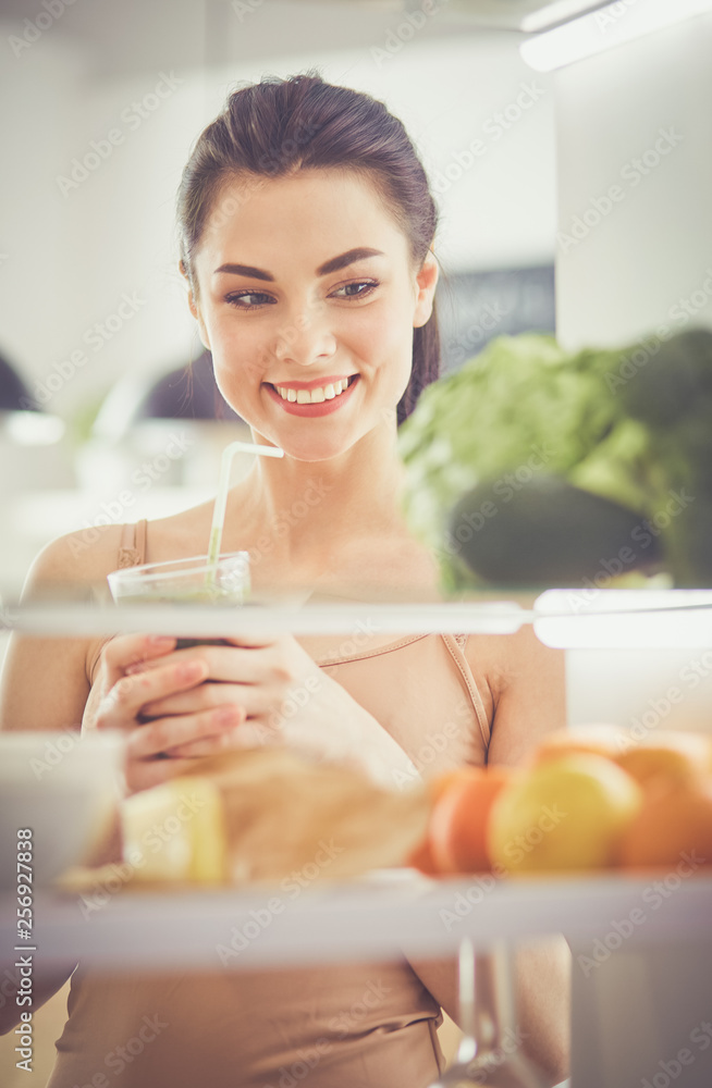 Smiling woman taking a fresh vegetable out of the fridge, healthy food concept