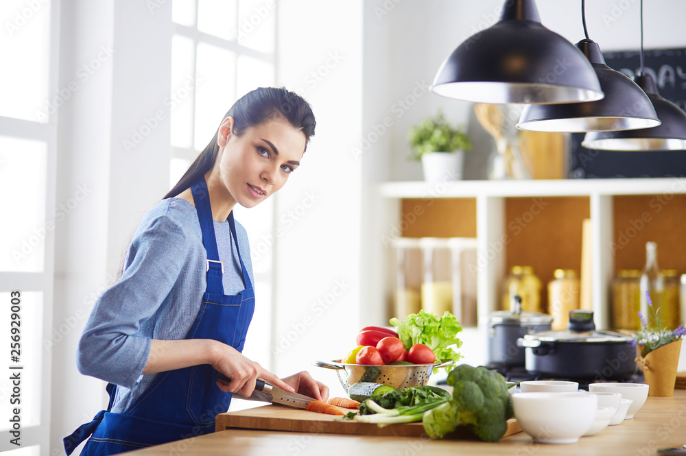 Young woman cutting vegetables in kitchen at home