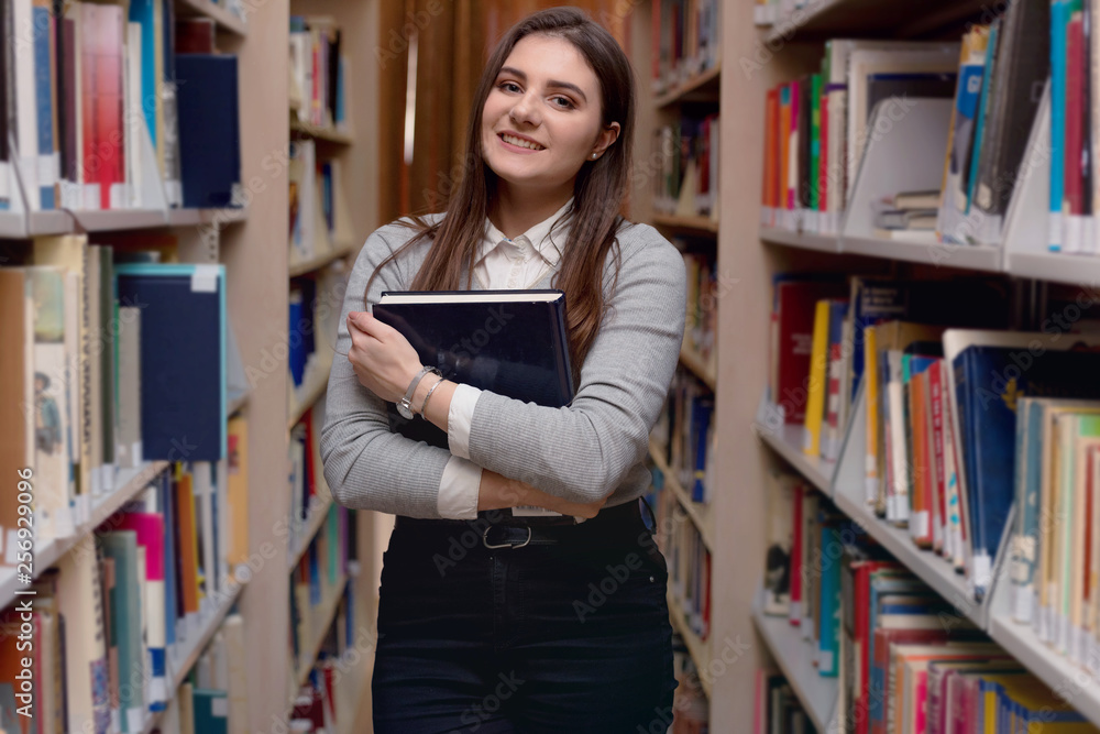 Beautiful adult female international student spending break at university library. searching for necessary literature lesson. Standing near bookshelves. Beautiful adult female international student spending break at university library. searching for necessary literature lesson. Standing near bookshelves.