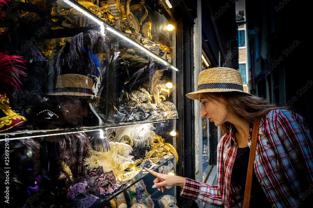 Young woman who chois a Venetian mask in shop