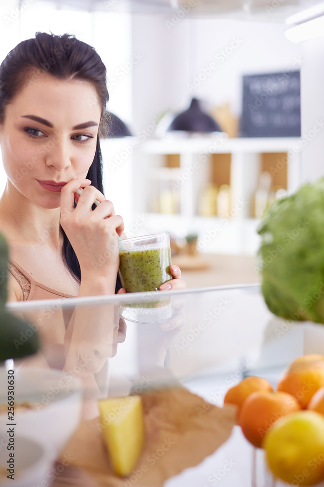 Smiling woman taking a fresh fruit out of the fridge, healthy food concept