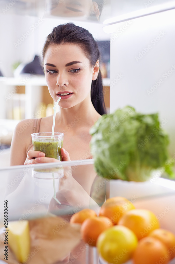 Smiling woman taking a fresh vegetable out of the fridge, healthy food concept Smiling woman taking a fresh vegetable out of the fridge, healthy food concept