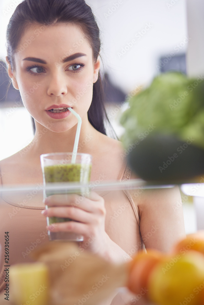 Smiling woman taking a fresh vegetable out of the fridge, healthy food concept Smiling woman taking a fresh vegetable out of the fridge, healthy food concept