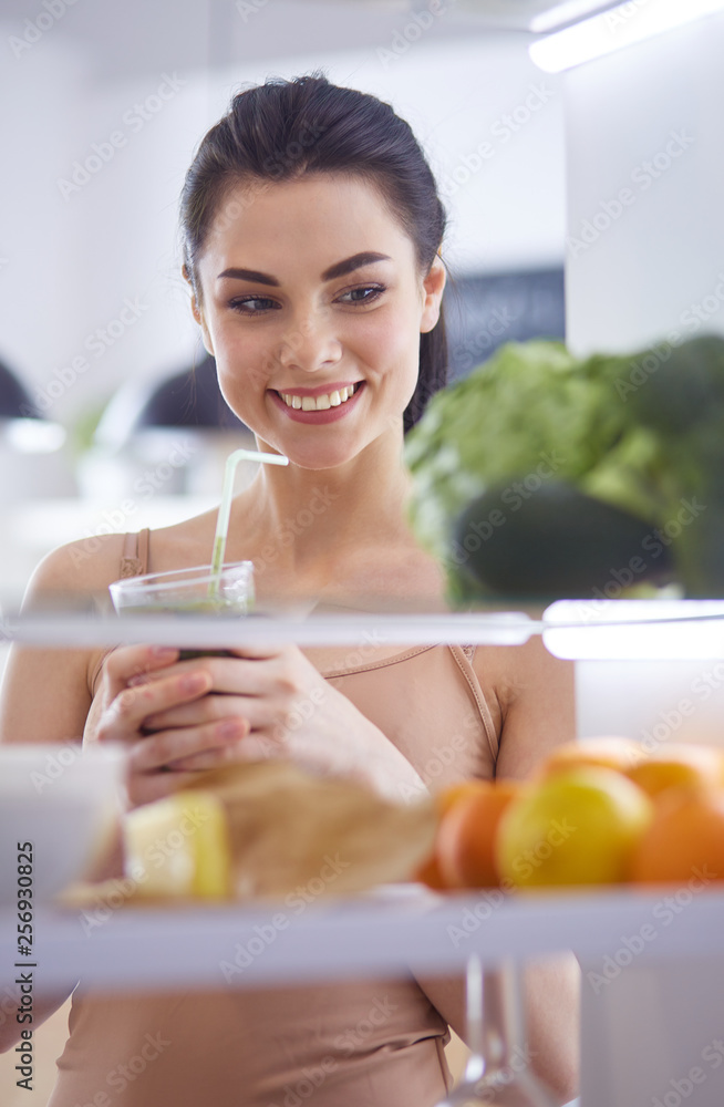 Smiling woman taking a fresh vegetable out of the fridge, healthy food concept Smiling woman taking a fresh vegetable out of the fridge, healthy food concept