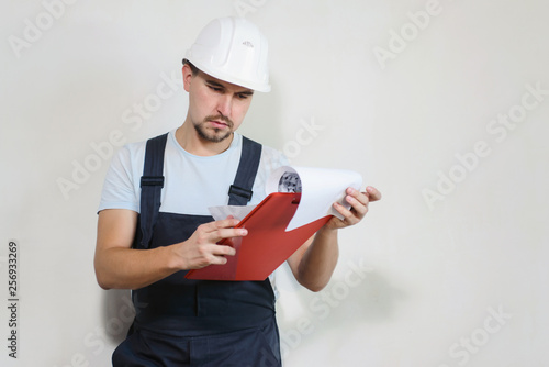 Portrait of young man worker industrial engineer in uniform and helmet at white background. Safety equipment. Home renovation concept. Copyspace for text