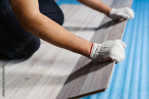 Close up hands of man installing new laminated wooden floor. Laminate flooring home renovation . Copyspace for text