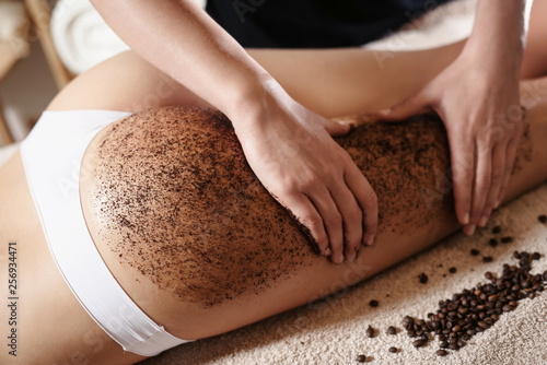 Obraz na plátně Close up of woman getting buttocks and legs massage with coffee scrub at spa