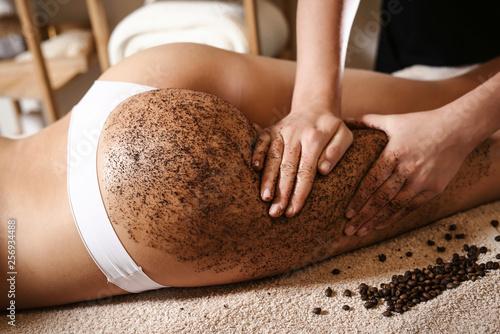 Fototapeta Close up of woman getting buttocks and legs massage with coffee scrub at spa