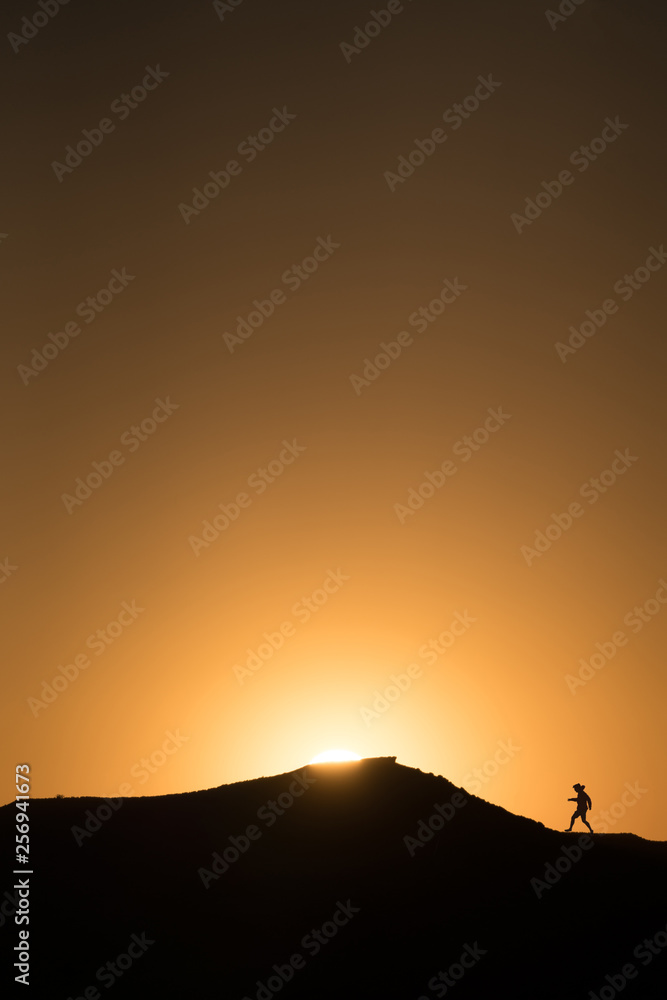 Silhouette of a person running up a mountain