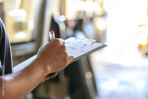 Mechanic holding clipboard with checking truck in service center,.Preforming a pre-trip inspection on a truck,preventive maintenance,spot focus