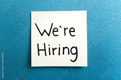 Concept of hiring and job. Adhesive note on blue fabric cloth background texture