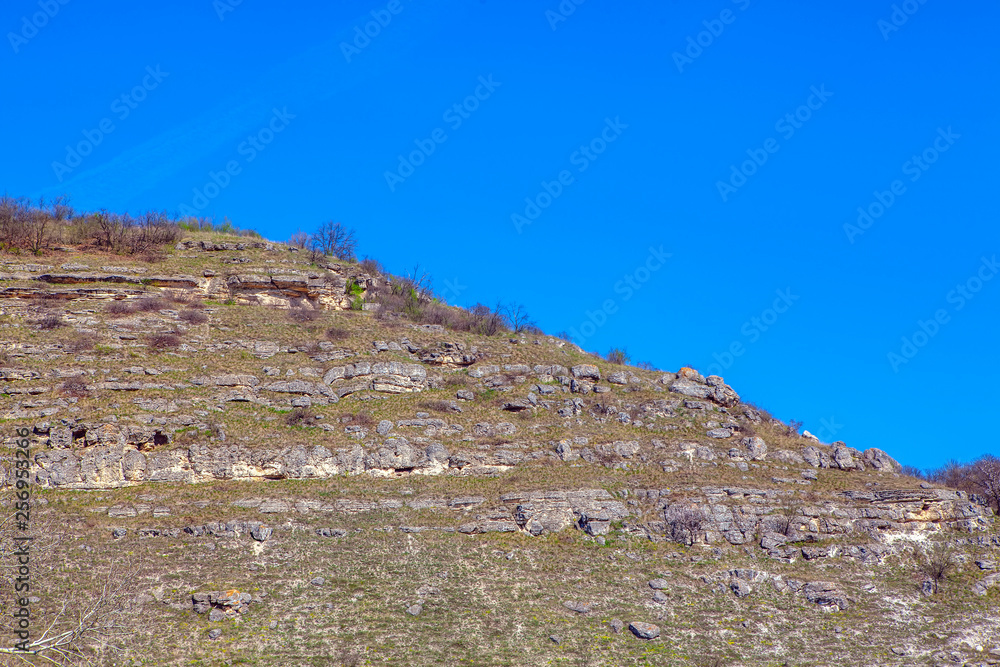 grey mountain with rocks against blue sky 