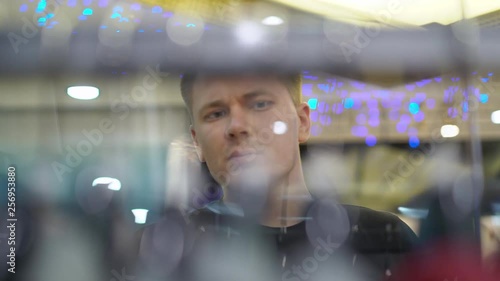 Young attractive man looking at shop window with men's fashion suits in the mall