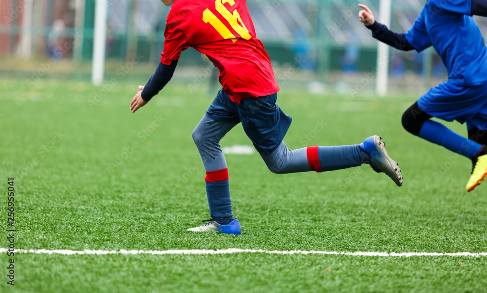 Obraz premium Football training for kids. Boys in blue red sportswear on soccer field. Young footballers dribble and kick ball in game. Training, active lifestyle, sport, children activity concept 