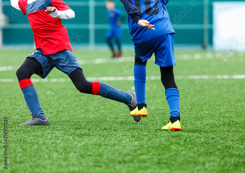 Football training for kids. Boys in blue red sportswear on soccer field. Young footballers dribble and kick ball in game. Training, active lifestyle, sport, children activity concept 