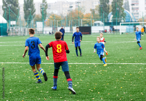 Boys in red white blue sportswear running on soccer field. Young footballers dribble and kick football ball in game. Training, active lifestyle, sport, children activity concept © Natali