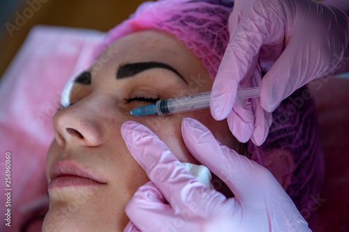 Doctor cosmetologist makes Rejuvenating facial injections procedure for tightening and smoothing wrinkles on face skin of beautiful, young woman in beauty salon.Cosmetology skin care.