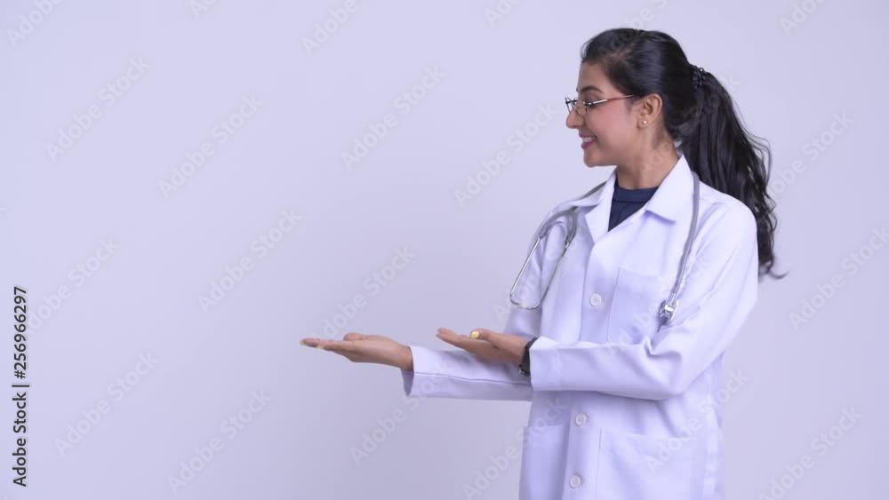 Young happy Persian woman doctor showing something Young happy Persian woman doctor showing something
