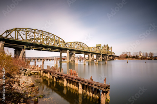 Long exposure of a river crossing underneath a metal bridge