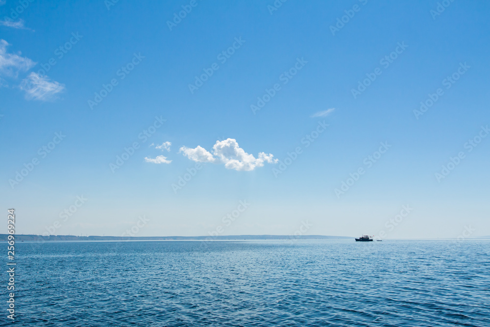 Blue sky with clouds above the water surface.