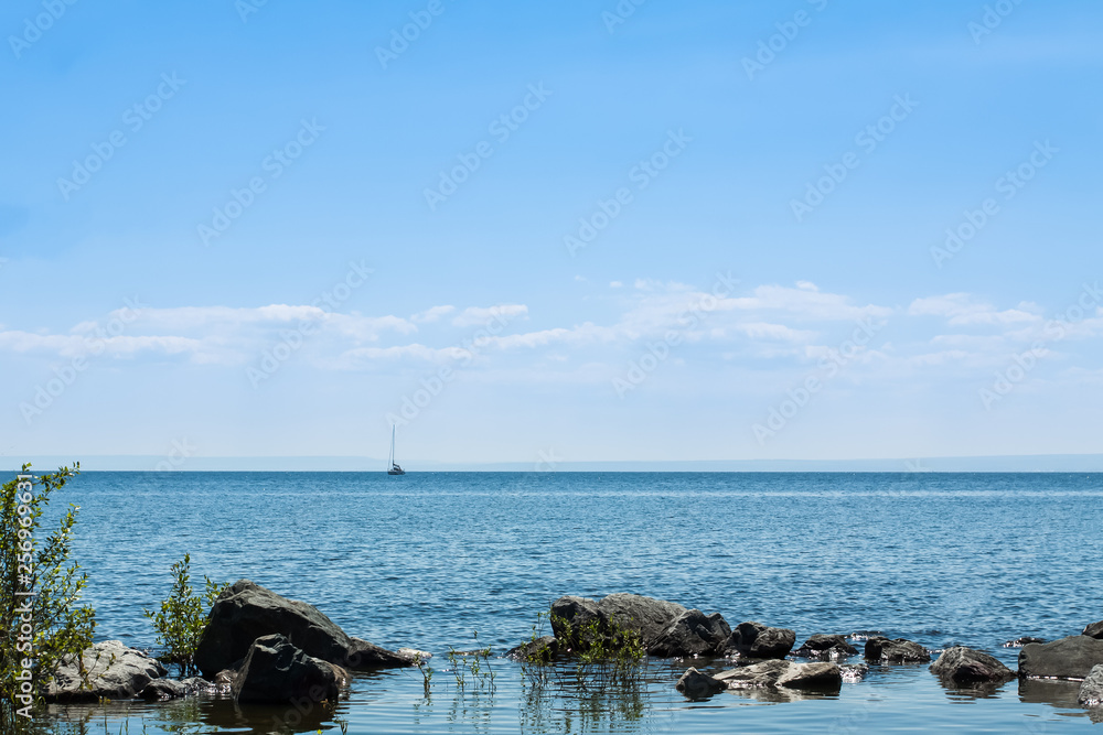 Sailboat in the distance against the blue sky on a Sunny day.