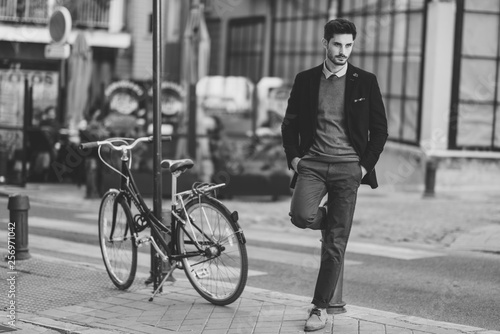 Man wearing british elegant suit in the street near an old bycicle