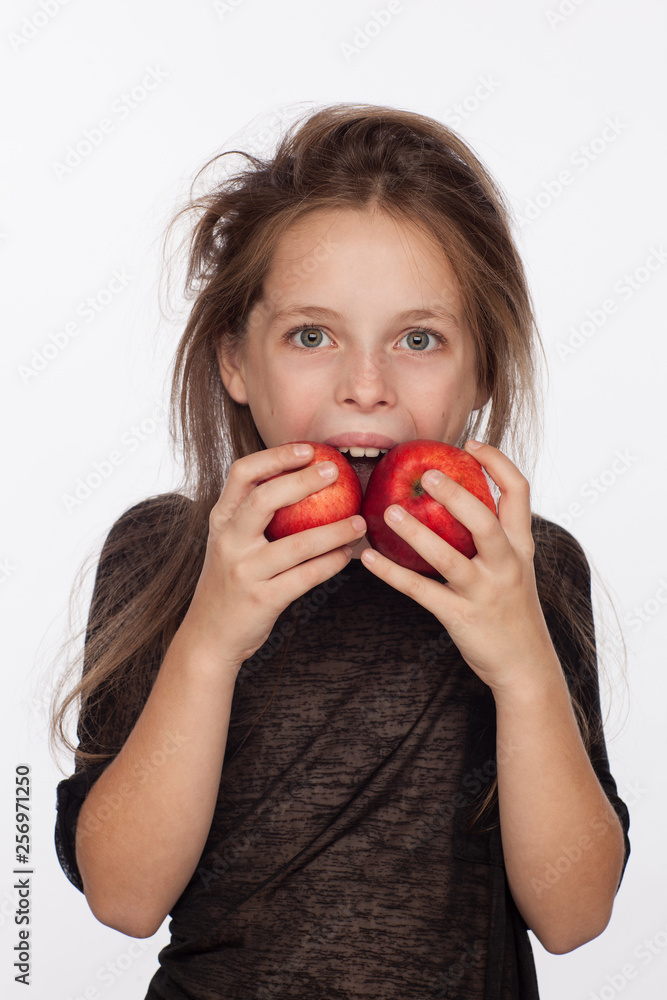 Beautiful emotional eight-year-old girl with apples. Photo session in the studio. The girl is wearing a black blouse Beautiful emotional eight-year-old girl with apples. Photo session in the studio. The girl is wearing a black blouse