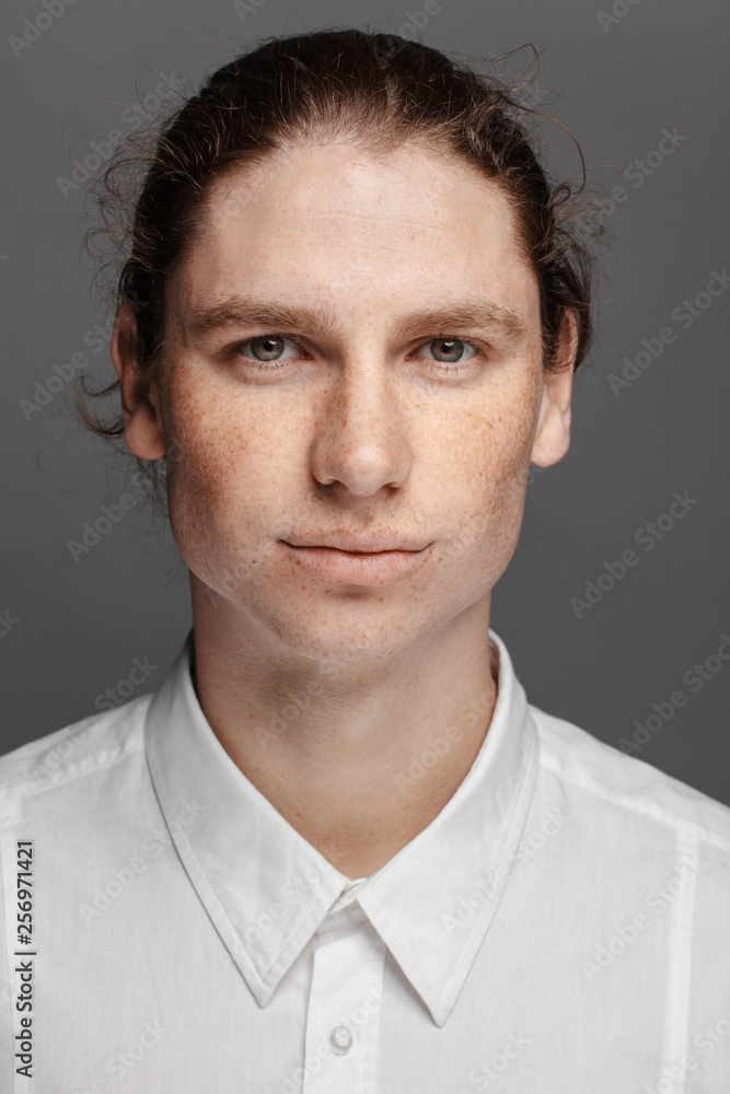 Portrait of a handsome long-haired man with drawn hair and freckles dressed in a white shirt Portrait of a handsome long-haired man with drawn hair and freckles dressed in a white shirt