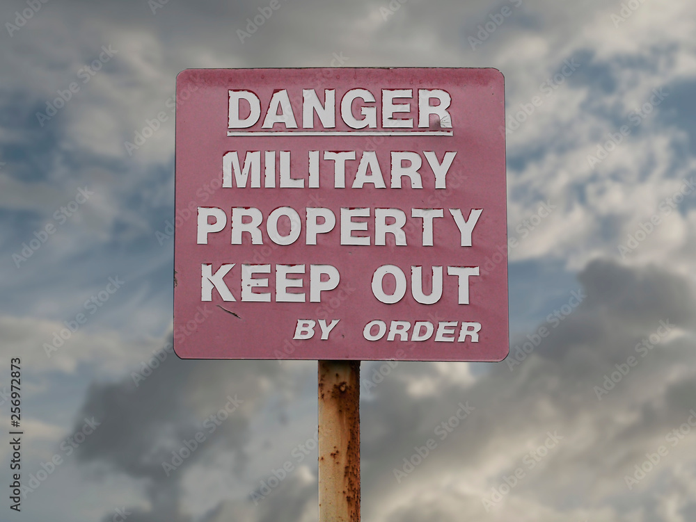 Old war warning sign: Danger keep out. Cloudy sky in the backgrund. Old war warning sign: Danger keep out. Cloudy sky in the backgrund.
