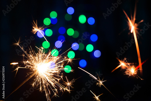 Bengal fire on a black background and blurred bokeh blue lights  new year texture . A lot of sparks