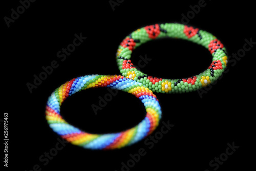 Two kid's summer bracelets made of seed beads isolated on a black background close up
