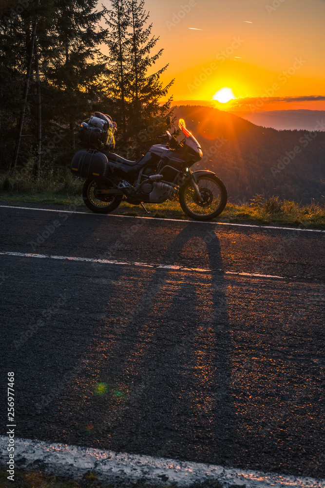 Adventure motorcycle, silhouette touristic motorbike. the mountain peaks in the sunset. Copy space. Concept of Tourism, adventures, active lifestyle, Transfagarasan, Romania, vertical photo