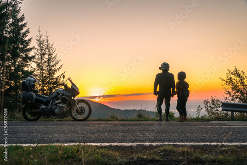 Silhouette of biker couple girl man and adventure motorcycle on the road with sunset light. Top of mountains  tourism motorbike  vacation active lifestyle  happy together. Transfagarasan  Romania.