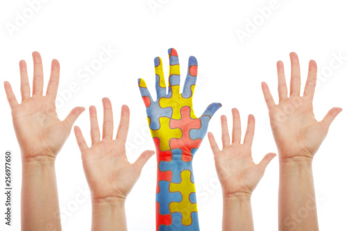 human hands, one patterned with many puzzle pieces of different colors. Autism awareness cocept