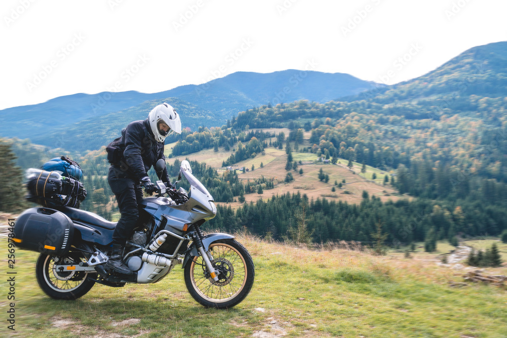 A motorcyclist ride on his touristic motorcycle, with big bags ready for a long trip, black style, white helmet, ride, adventure, outdoor activities, mountain road in Romania A motorcyclist ride on his touristic motorcycle, with big bags ready for a long trip, black style, white helmet, ride, adventure, outdoor activities, mountain road in Romania