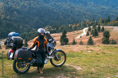 Woman biker with big adventure motorbike, motorcyclists vacation, world traveler, long road trip on two wheels. autumn day. Mountains on background. Romania © Sergey