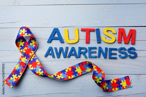 Obraz na plátně World Autism awareness and pride day or month with Puzzle pattern ribbon on blue wooden background