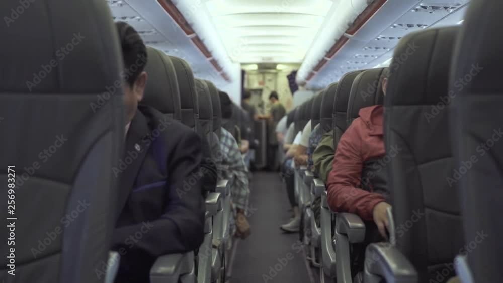 Passengers sitting on seats aircraft while flying in sky. Passengers inside cabin commercial plane while flight. Air traveling by modern commercial airplane. Passengers sitting on seats aircraft while flying in sky. Passengers inside cabin commercial plane while flight. Air traveling by modern commercial airplane.