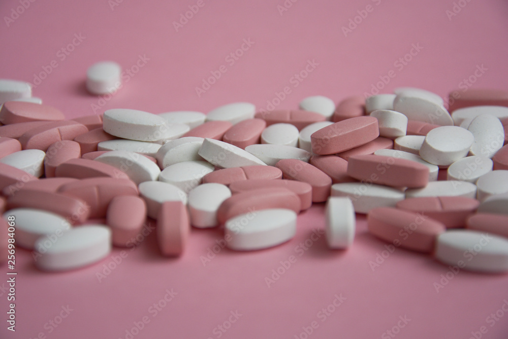 lots of pink and white pills on a pink background