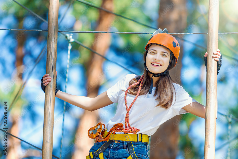 Φωτογραφία Young beauty female woman adult wears protective helmet having fun in extreme rope park, amusement park